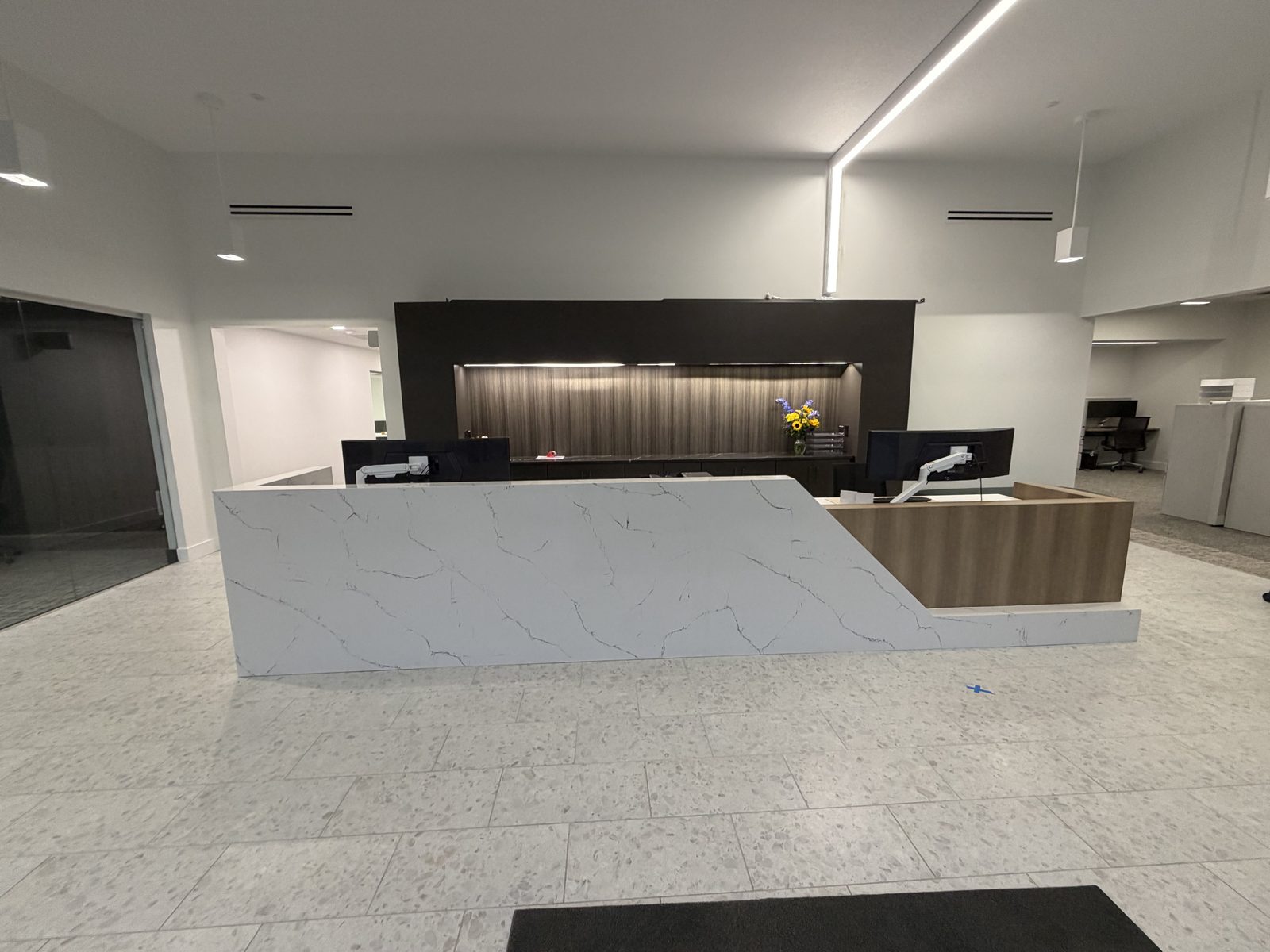 Custom reception desk with Cambria quartz waterfall and woodgrain laminate for Garmann Miller offices